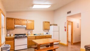 A kitchen with wooden cabinets, a stove, a microwave, and a refrigerator. - Frio Country Resort - Within walking distance to the Frio River! (Concan)