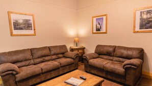 A living room with two brown leather sofas, a wooden coffee table, and a small side table with a lamp. - Frio Country Resort - Within walking distance to the Frio River! (Concan)