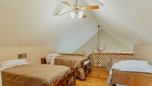 Una stanza con due letti di legno, un ventilatore a soffitto e pavimento in legno.