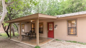 A single-story building with a covered patio area, a red door, and a number 22 sign. - Frio Country Resort - Within walking distance to the Frio River! (Concan)