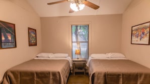 A bedroom with two beds, a ceiling fan, a window with blinds, and framed artwork on the walls. - Frio Country Resort - Within walking distance to the Frio River! (Concan)
