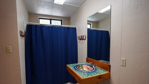 Un bagno con tenda da doccia blu, un lavandino piastrellato con decorazione a mosaico e un mobile bagno in legno.