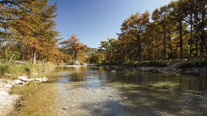 A clear river with a rocky bed, surrounded by trees with autumn foliage. - Frio Country Resort - Within walking distance to the Frio River! (Concan)
