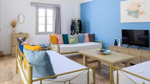A modern bedroom with a bed, a sofa, a TV, and a small table.
