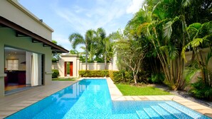 A swimming pool with a tiled edge, surrounded by a well-maintained lawn and palm trees. - Luxe 2br Pool Villa Walk to Bangtao Beach (Choeng Thale)