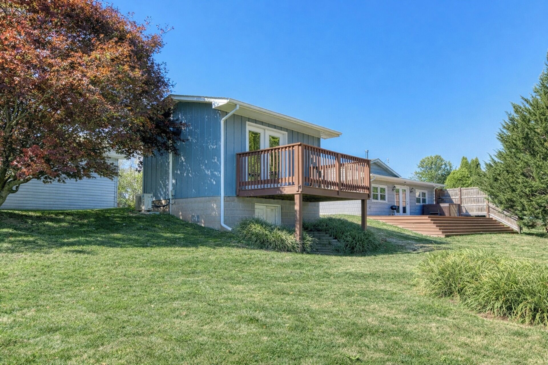 A two-story house with a balcony, a front yard, and a wooden deck.