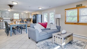 A modern kitchen with white cabinets, a black refrigerator, and a dining area with blue chairs. - New River 3BR - Fishing, Kayaking, Hot tub, VT Game Weekends (Belspring)