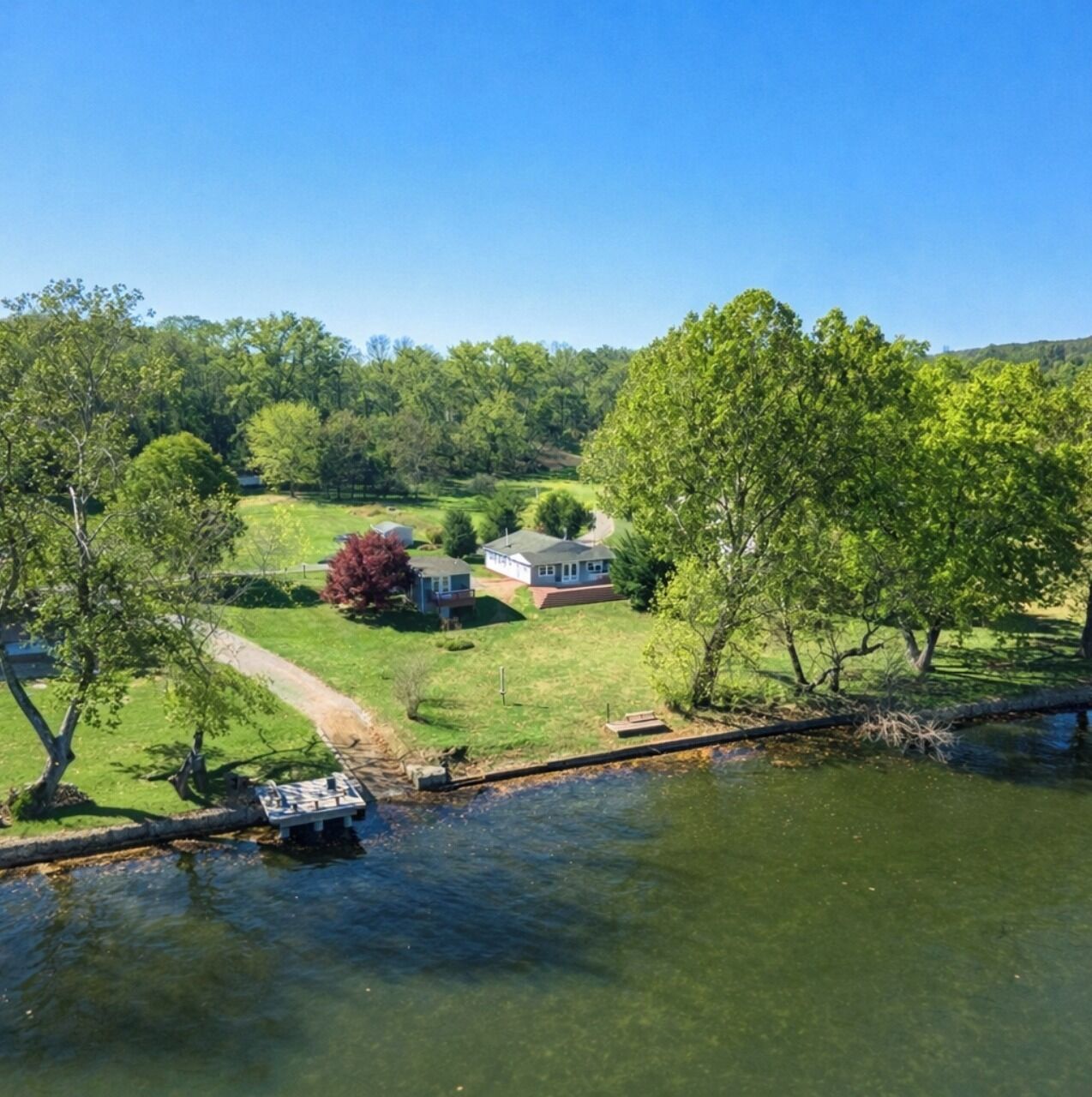 A house with a lawn and a small dock by a body of water.