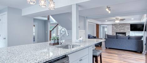A modern kitchen with granite countertops, stainless steel appliances, and pendant lighting.
