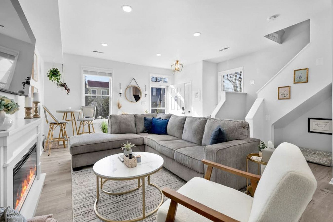 A modern living room with a grey sectional sofa, a round coffee table, and a fireplace.