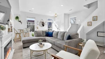 A modern living room with a grey sectional sofa, a round coffee table, and a fireplace.