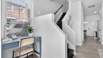 A modern interior with a desk, chair, and staircase.