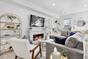 Una sala de estar moderna con chimenea, asientos cómodos y un televisor de pantalla plana.