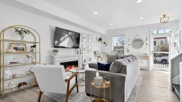 A modern living room with a fireplace, a sofa, a TV, and a bookshelf.