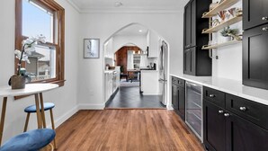 A modern kitchen with dark cabinetry, a white countertop, and a wooden floor. - Centrally Located Arlington Bungalow (Arlington)