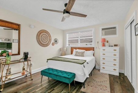 A bedroom with a bed, a ceiling fan, a dresser, a bench, a mirror, and a window with blinds.. Cozy Queen Studio Stay: Heart of Safety Harbor