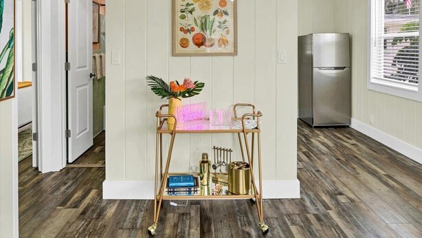A kitchen with a wooden floor, a stainless steel refrigerator, and a wall-mounted fruit illustration.