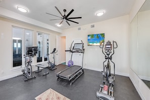 A gym with treadmills, elliptical machines, and a ceiling fan. - Walk to Beach Pet Friendly Resort Rental (Corpus Christi)
