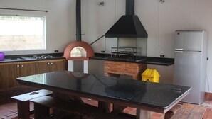 Eine Küche mit Gasherd, Backofen, Kühlschrank und einem Fenster mit Blick ins Freie.