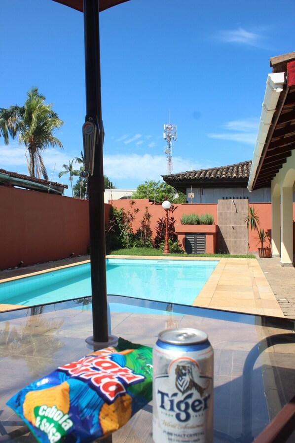 Une vue sur la piscine, avec une canette de bière Tiger et un paquet de chips sur une table.