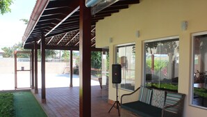 Ein überdachter Außenbereich mit Korbuschen, einem Lautsprecher und Blick auf einen Swimmingpool.