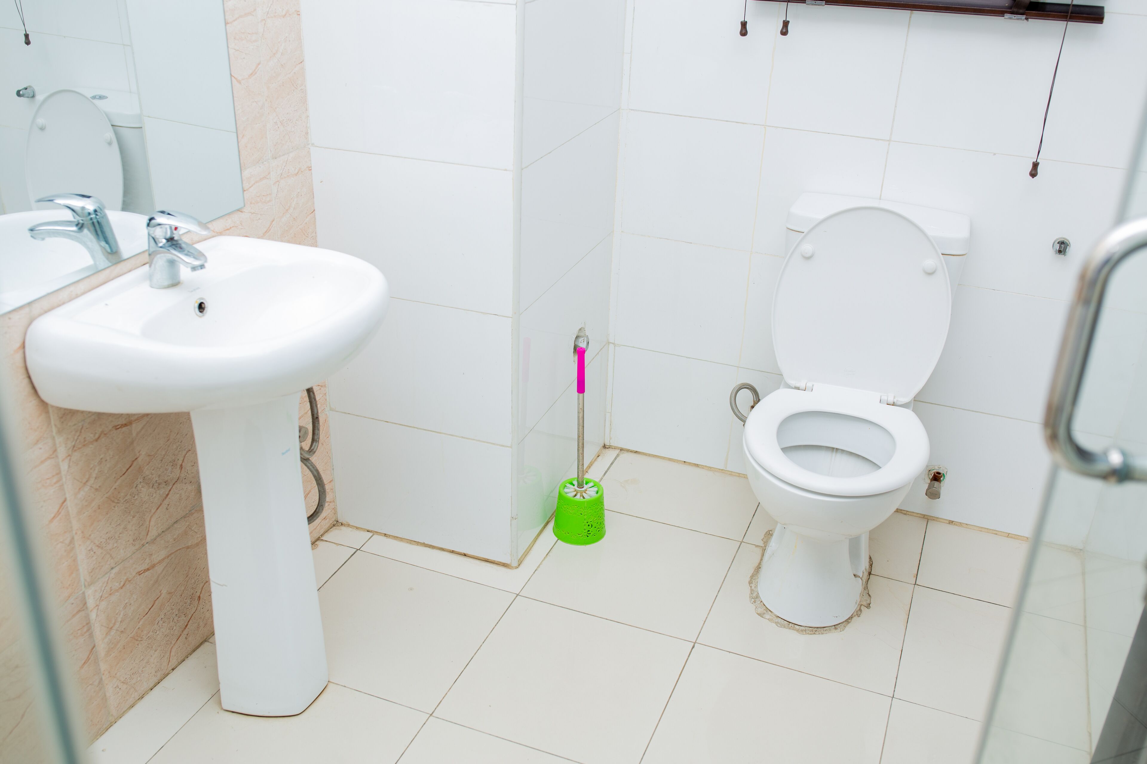 A bathroom with a white sink, toilet, and a green mop.