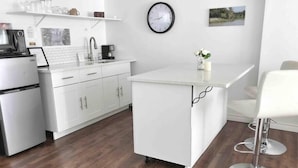 A modern kitchen with white cabinets, a stainless steel refrigerator, a coffee machine, and a clock on the wall. - Romantic Couples Getaway Sauna, Hot Tub, Private Beach access, Hiking trails (Port Franks)
