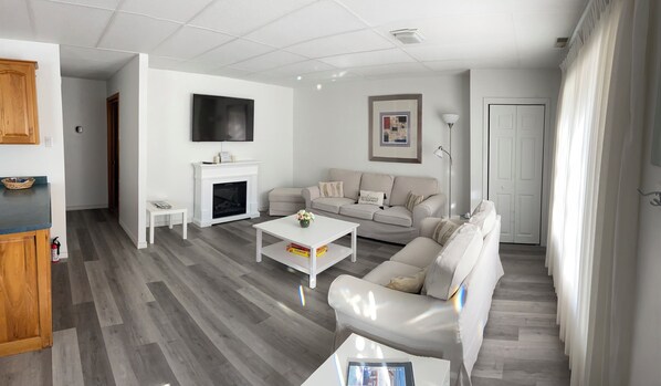 A modern living room with a fireplace, a sofa, a coffee table, and a television.