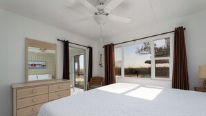 Une chambre à coucher avec un grand lit, une commode, un miroir et une fenêtre avec des rideaux.