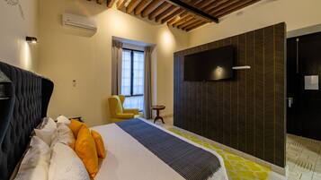 Ein Hotelzimmer mit Bett, Sessel, Fernseher und einer Wand mit Muster.
