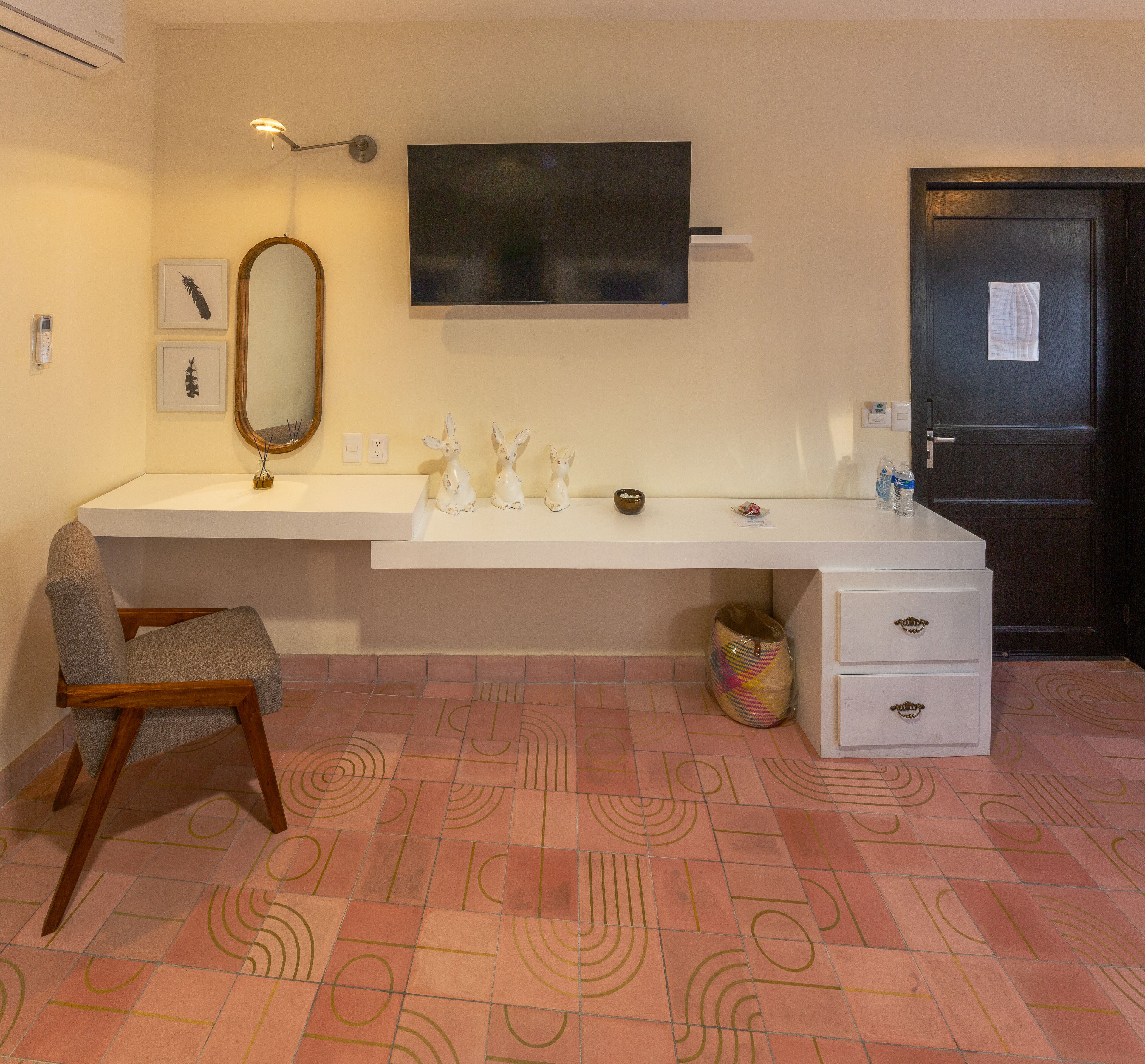 Un baño moderno con un tocador blanco, un espejo y un televisor de pantalla plana sobre el espejo.