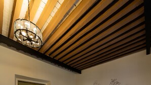 Un dormitorio con una cama, un sofá azul oscuro, un tapete estampado, un techo de madera y una pared con dibujos de corazones.