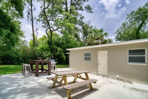 Relax on the patio surrounded by lush greenery and enjoy dining or unwinding at the wooden table and benches.