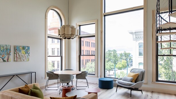 A spacious living room with large windows, a round table, and modern furniture. - Flat 301 Front and Union (Traverse City)