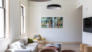 A modern living room with a sofa, armchairs, a coffee table, and a painting on the wall. - Flat 203 Front and Union (Traverse City)