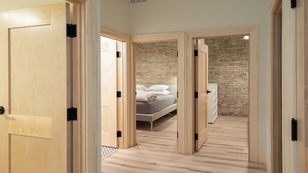 A bedroom with a bed, a brick wall, and wooden flooring. - Flat 203 Front and Union (Traverse City)