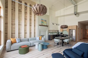 A modern living room with a grey sofa, round coffee table, and a dining area with a table and chairs.