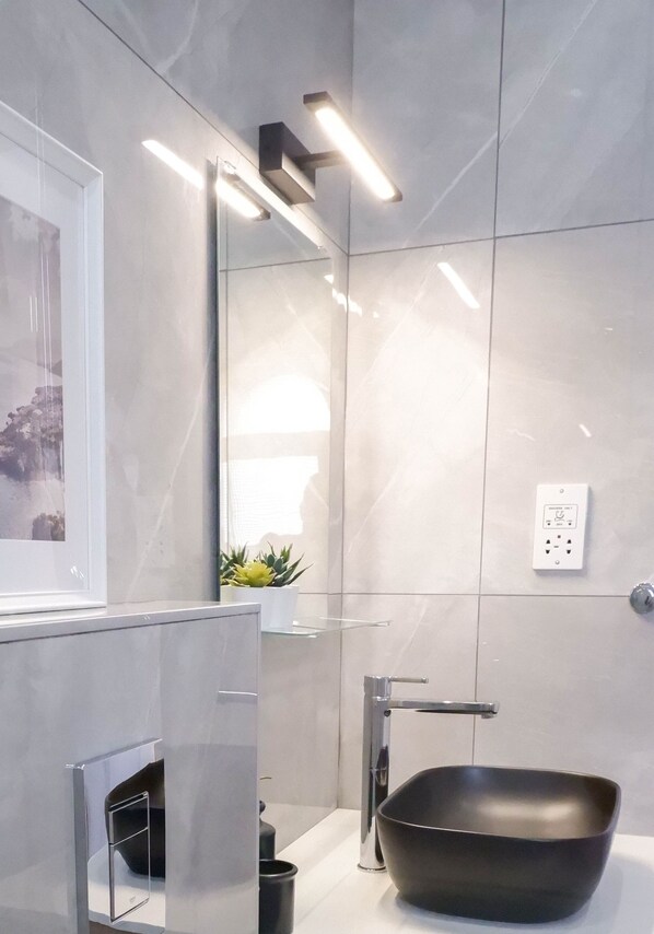 A modern bathroom with a large mirror, a black vessel sink, and a sleek faucet. - Procy 103 Sea View Apartment Ideal for Long or Short Stays (Paphos)
