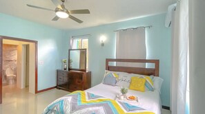 Une chambre à coucher avec un lit, une commode, un miroir et un ventilateur de plafond.