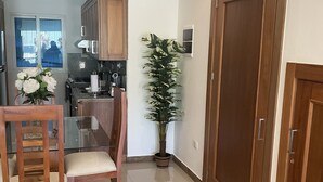 A modern kitchen with wooden cabinets, a dining table with chairs, a potted plant, and a large wooden door. - "Stylish and beautiful Condo located in Sosua" (sosua)