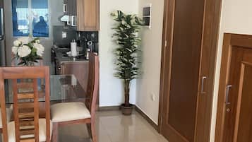 A modern kitchen with wooden cabinets, a dining table with chairs, a potted plant, and a large wooden door.