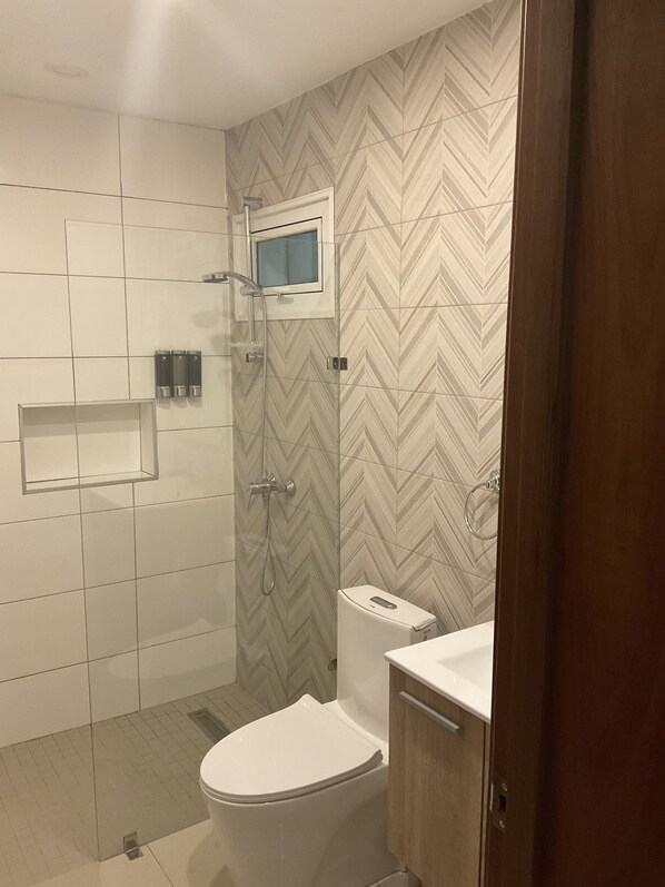 Un baño moderno con ducha, inodoro y lavamanos.