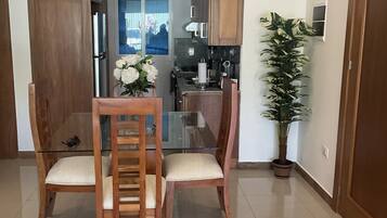 A modern kitchen with wooden cabinets, a glass dining table, and two chairs.