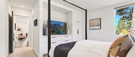 A bedroom with a four-poster bed, a large wardrobe, and a television on a dresser.