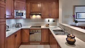 A modern kitchen with wooden cabinets, stainless steel appliances, and a built-in oven. - Apartment Two Weeks Right of Use at Radisson Blu Resort & Spa, Golden Sands (Mellieha)