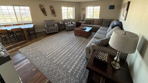 A spacious living room with a sofa, armchairs, a coffee table, and a dining area with a table and chairs. - Powderhorn Slopeside 3 Bedroom / 3.5 Bath Condo Next to Ski Lift (Mesa)