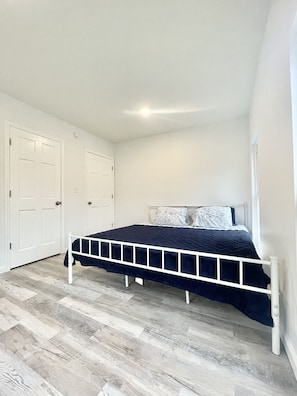 A bedroom with a bed, white doors, and a wooden floor. - Great house for groups! (Oneonta)