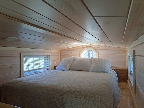 A bedroom with a bed, a window, and a sloped ceiling. - Tiny Home (Beaver Dams)
