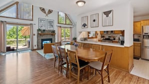 Un comedor amplio con una mesa y sillas de madera, una cocina con electrodomésticos modernos y una chimenea.