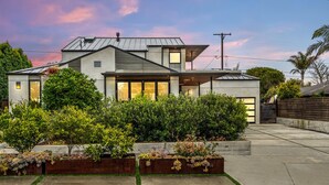 A modern two-story house with a large front yard, a garage, and a well-maintained garden.